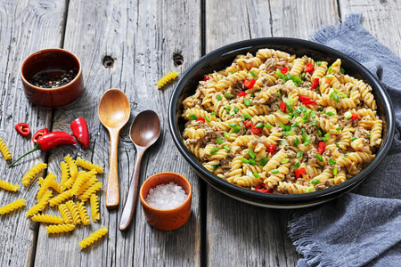creamy ground beef pasta, cheeseburger fusilli pasta sprinkled with green onion and chili pepper in a bowl on rustic grey wood table, horizontal view, not AI generatedの写真素材