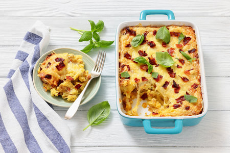twice baked potato casserole with fried bacon and cheddar cheese in a baking dish on white wood table, horizontal view, not AI generatedの写真素材