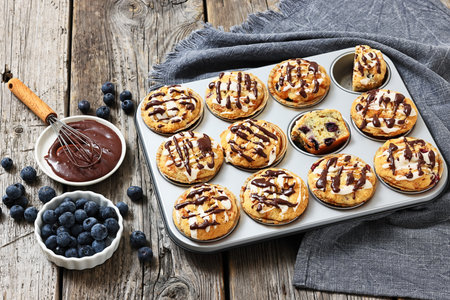 blueberry muffins in a muffin pan sprinkled with lemon chocolate glaze on rustic wood table with fresh berries, horizontal view, not AI generatedの写真素材