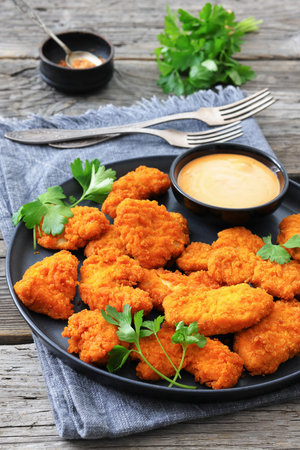 air fryer breaded chicken breast chunks with tangy dipping sauce on a plate on rustic wood table, vertical view from above, close-up, not AI generatedの写真素材
