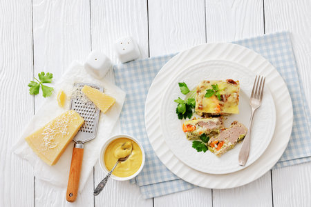 Ground beef vegetables casserole plated on a white plate with fork on white wood table, horizontal view from above, flat lay, free space, not AI generatedの写真素材