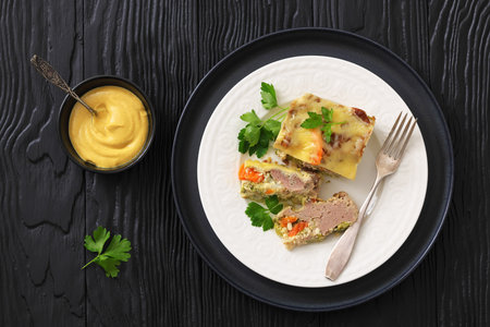 Cheesy ground beef vegetables casserole plated on a white plate with fork on black wood table, horizontal view from above, flat lay, not AI generatedの写真素材