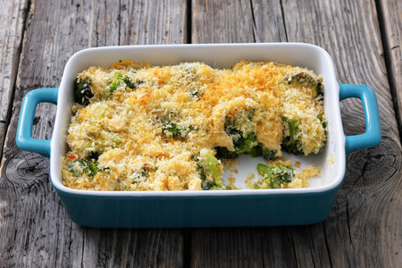 crunchy baked broccoli topped with panko breadcrumbs and parmesan cheese in a baking dish on rustic wood table, close-upの写真素材