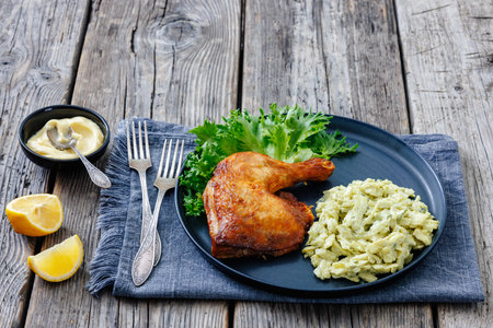 roast chicken leg with cabbage artichoke salad on a plate on rustic wood table with lemon and mayonnaise, close-up, not AI generatedの写真素材