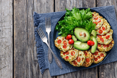 ground chicken cherry tomatoes patties plated with fresh lettuce and avocado slices on a plate on...