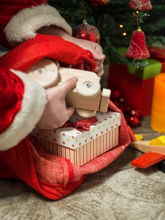 holidays, celebration and people concept - close up of santa claus putting present under christmas treeの写真素材