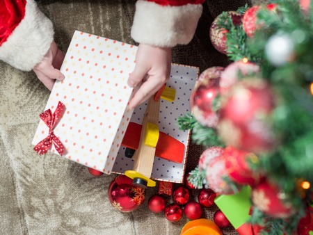 Santa Claus at Home putting gifts under Christmas Treeの写真素材