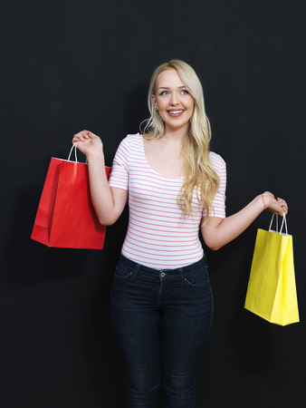 Blonde girl with shopping bags on a chalkboard backgroundの写真素材