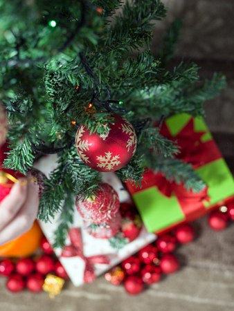 Close-up of man hanging decorative toy ball on Christmas tree branchの写真素材