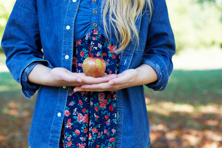 Apple woman. Very beautiful ethnic model eating red apple in the park.の写真素材