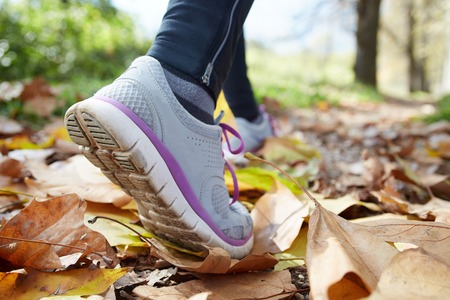 close up of feet of a runner running in autumn leaves training for marathon and fitness healthy lifestyleの写真素材