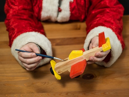 Santa Claus sitting in his workshop painting a toy airplane. Horizontal composition.の写真素材