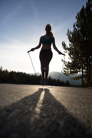 Sporty woman skipping at promenade on a sunny day, retro toneの写真素材