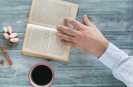 Man reading a book and writing notes on wooden tableの写真素材