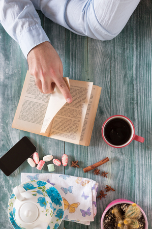 Man reading a book and writing notes on wooden tableの写真素材