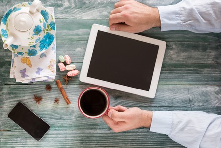 hand using mockup tablet similar to ipad style on wood desk white display with clipping path screen easy add imageの写真素材