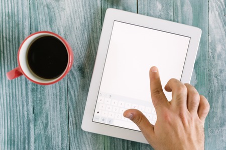 hand using mockup tablet similar to ipad style on wood desk white display with clipping path screen easy add imageの写真素材