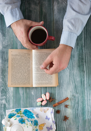 Man reading a book and writing notes on wooden tableの写真素材