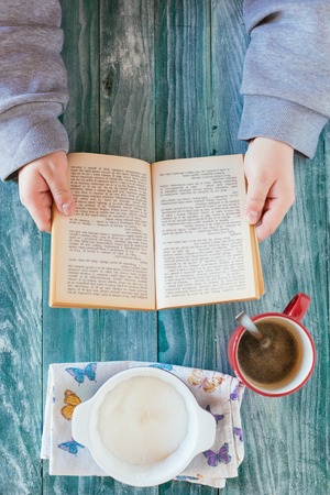 Man reading a book and writing notes on wooden tableの写真素材