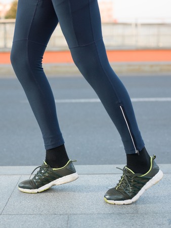 Close-up of Athlete shoes while running in park. Fitness concept with female athlete jogging in city parkの写真素材