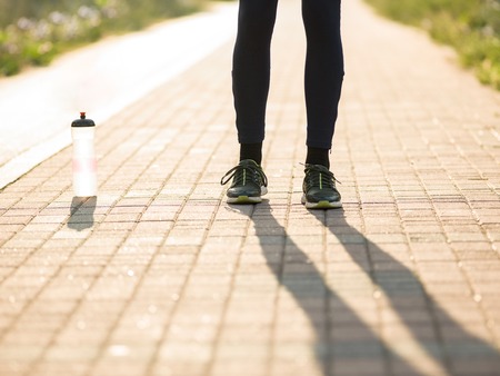 Portrait of a male runner tying sport shoe shoelace outsideの写真素材