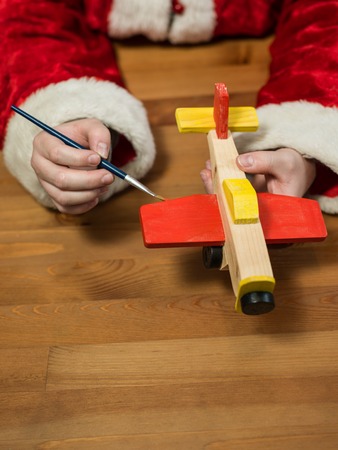 Santa Claus sitting in his workshop painting a toy airplane. Horizontal composition.の写真素材