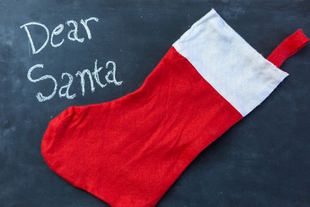 Color red and white chalk drawing of striped Christmas sock on black chalkboard backgroundの写真素材