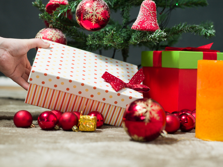 holidays, celebration and people concept - close up of santa claus putting present under christmas treeの写真素材