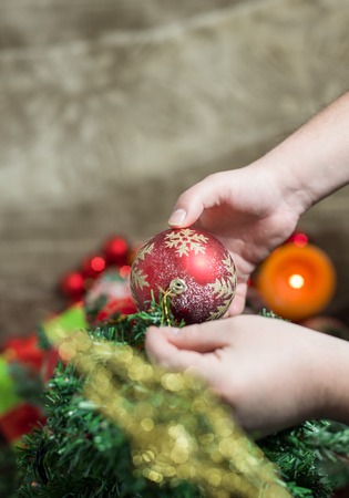 Close-up of man hanging decorative toy ball on Christmas tree branchの写真素材