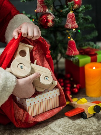 holidays, celebration and people concept - close up of santa claus putting present under christmas treeの写真素材