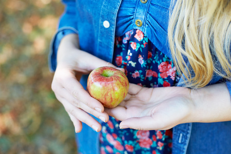Apple woman. Very beautiful ethnic model eating red apple in the park.の写真素材