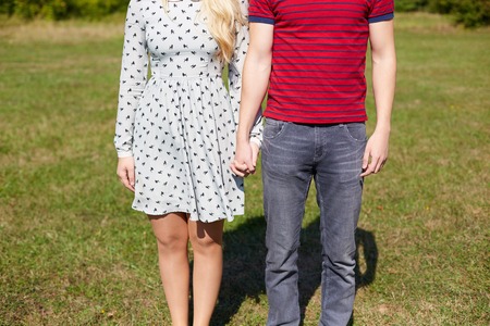 Couple holding hands with romantic view at the sunlit fieldの写真素材