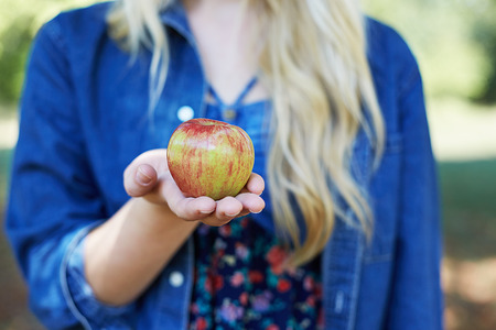 Apple woman. Very beautiful ethnic model eating red apple in the park.の写真素材