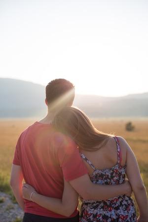Young couple enjoying the sunset in the meadowの写真素材