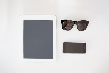 Tablet with clean screen on wooden table. Fashionable clothes sunglasses, hat, Flat mock up for design. Top view.の写真素材