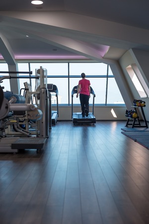 Man running in a gym on a treadmill concept for exercising, fitness and healthy lifestyleの写真素材