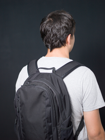Young man standing with travel backpack equipments isolated white backgroundの写真素材