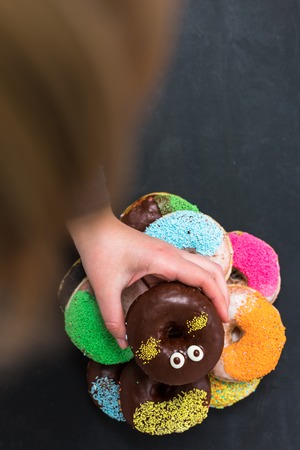 female  hand reaching to grab the doughnutの写真素材