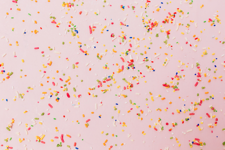 Colorful sprinkles spilled on pink textured backgroundの写真素材