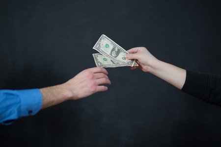 Businessman is paying in dollar bills, corruption and bribe concept.の写真素材