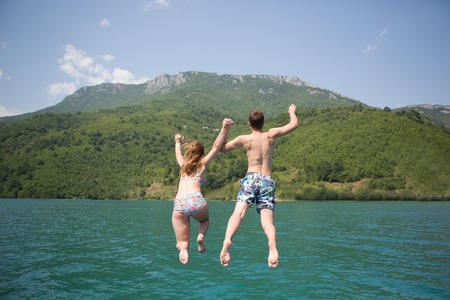 Young couple jumping on the edge of a boatの写真素材
