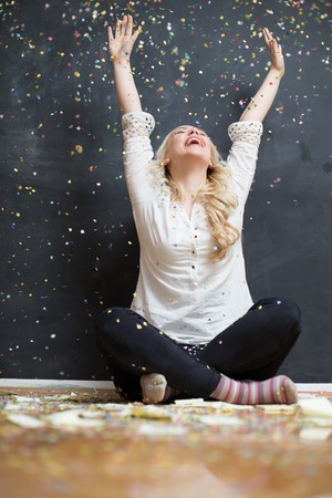 Cheerful young woman is stretching out her hands while confetti falling on herの写真素材