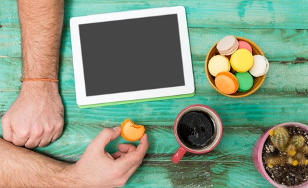 Man working at vintage rough wooden desk directly from above browsing electronic gadget drinking coffee mobile office phone . MAn using techology, morning coffeeの写真素材