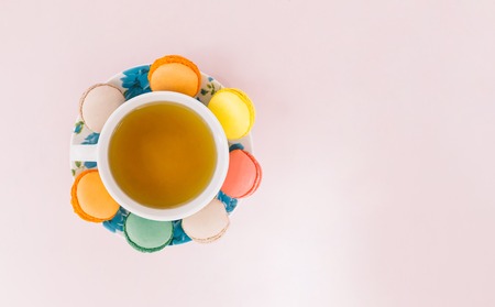 Colorful macaroons with cup of tea on pastel backgroundの写真素材