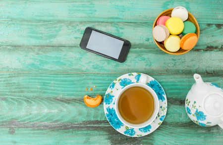 Mobile phone, tablet with coffee cup  and cakes on rustic  wooden table background - mockupの写真素材