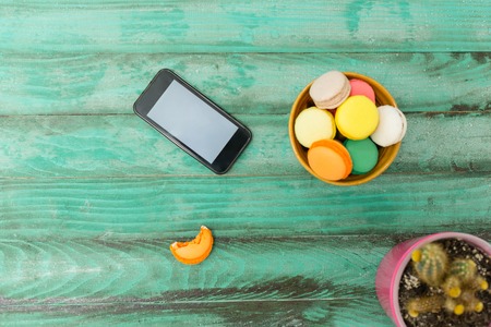 Mobile phone, tablet with coffee cup  and cakes on rustic  wooden table background - mockupの写真素材