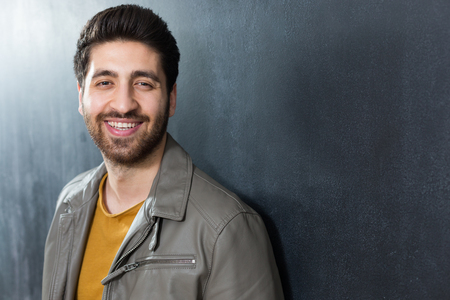 Handsome confident young man standing with folded arms against a dark background - fashion hipsterの写真素材