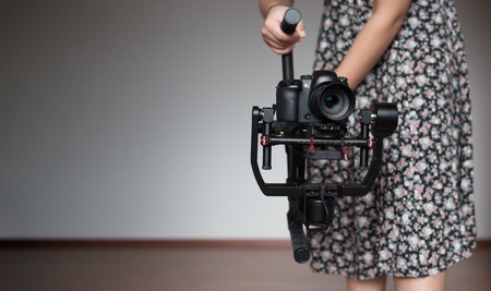 woman videographer using steady cam, Professional equipment helps to make high quality videoの写真素材