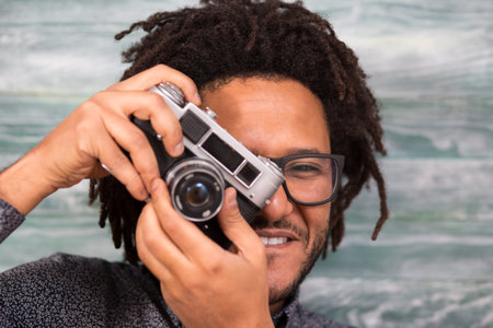 Happy hipster man smiling with toy camera on rustic backgorundの写真素材