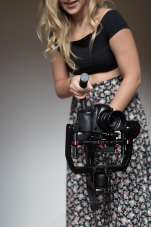 woman videographer using steady cam, Professional equipment helps to make high quality videoの写真素材